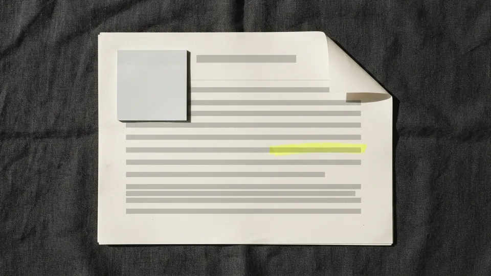 A printed report page with one yellow line, a pale grey sticky note and a curled top corner