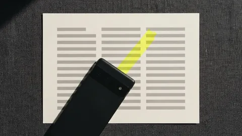 A phone lying face down across a printed page, with one yellow line showing past its edge