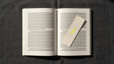 A paper bookmark with a small yellow mark lying across an open book