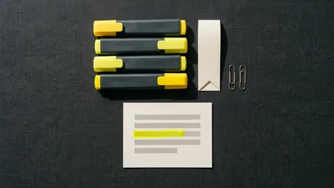 Four highlighter pens lined up beside a paper bookmark, two paper clips and a card with one yellow stroke